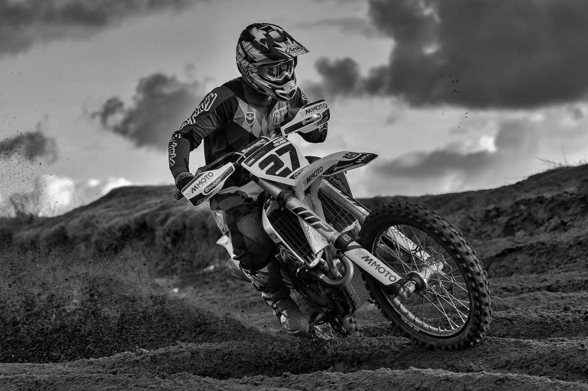 Dirt bike rider speeding through a muddy forest trail